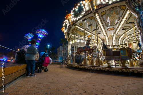 Children's vintage Carousel at an amusement park in the evening and night illumination. Beautiful, bright carousel in Alicante, Spain