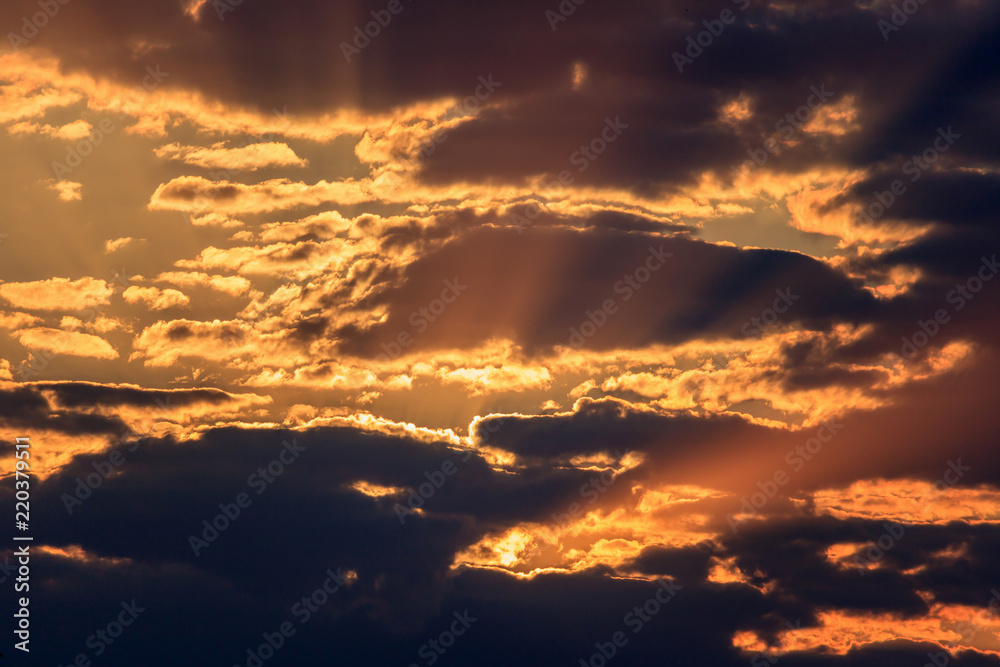 Dramatic sky with dark clouds and orange rays of the sun