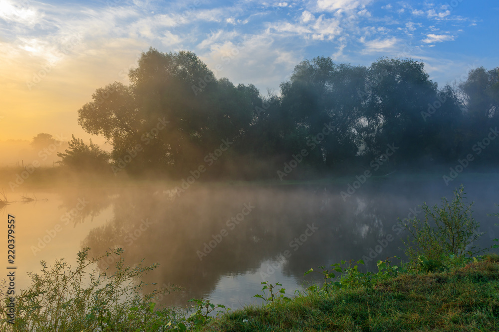 Fog above the river surface. River landscape on a sunny summer morning