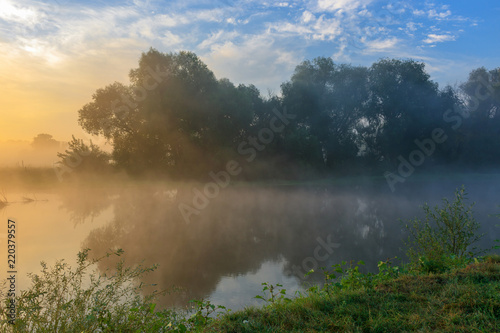 Fog above the river surface. River landscape on a sunny summer morning
