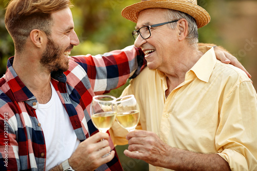 happy father and son tasting wine in vineyard. photo