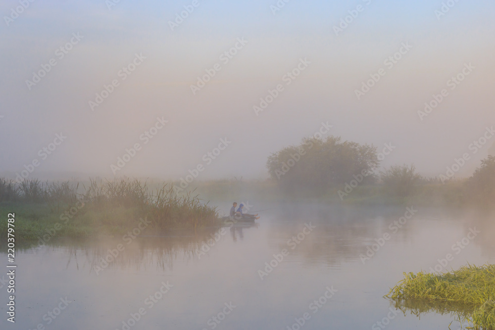 Two young men catching fish from an inflatable boat on the river in early morning. River landscape
