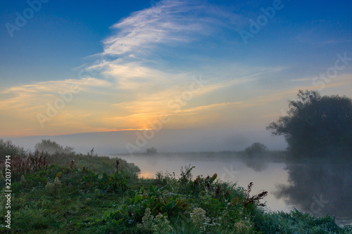 Sunrise on the river in early morning on a blue sky background. River landscape in summer morning