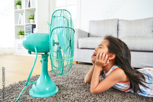 happy kid lying down in front of electric fan.