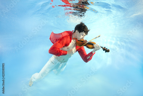 Obraz na plátně Teenager plays the violin underwater
