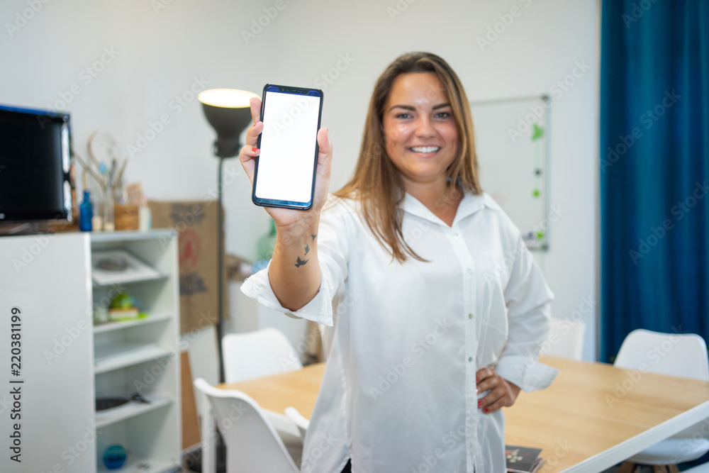 Young entrepreneur girl with the phone in her hand, showing her new app. The device screen is blank for your photomontage Young entrepreneur girl with the phone in her hand, showing her new app. The device screen is blank for your photomontage