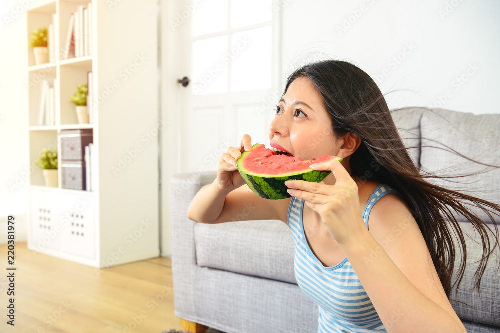 asian female taking a big bite of watermelon. asian female taking a big bite of watermelon.