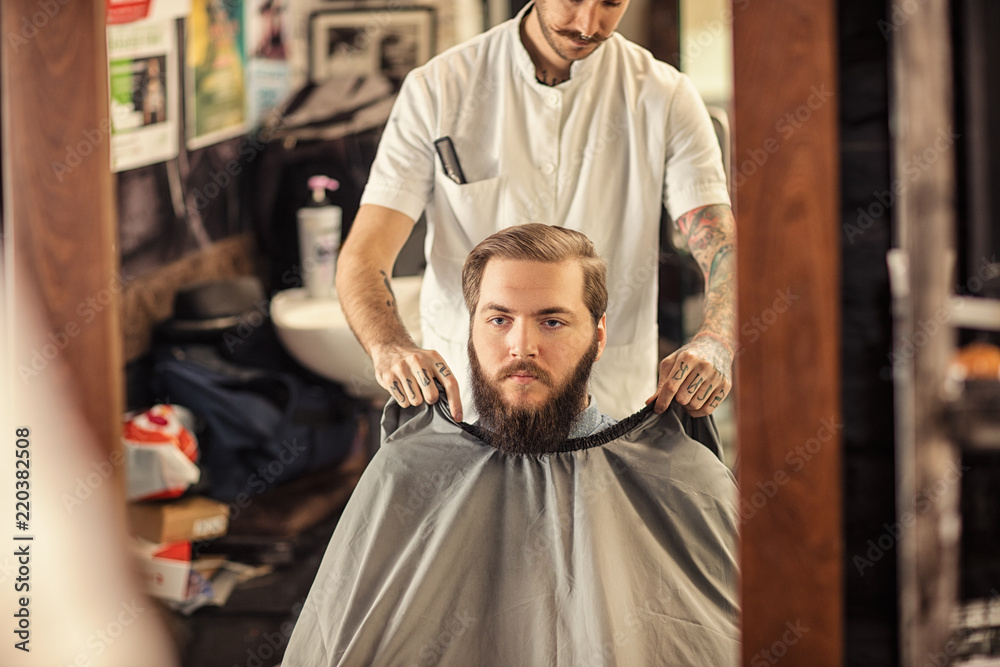 Barber put on apron around customer. Barber put on apron around customer.