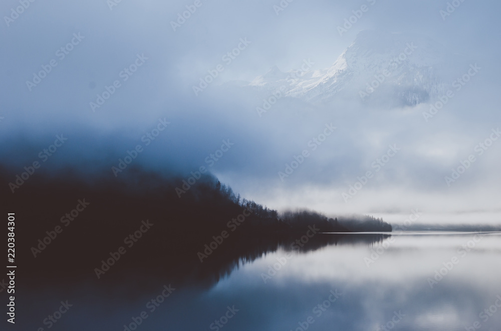 Fototapeta premium Delightful landscape view of Austrian Alps. Blue sunset over the early morning river covered with fog. Mountain seen over the clouds.