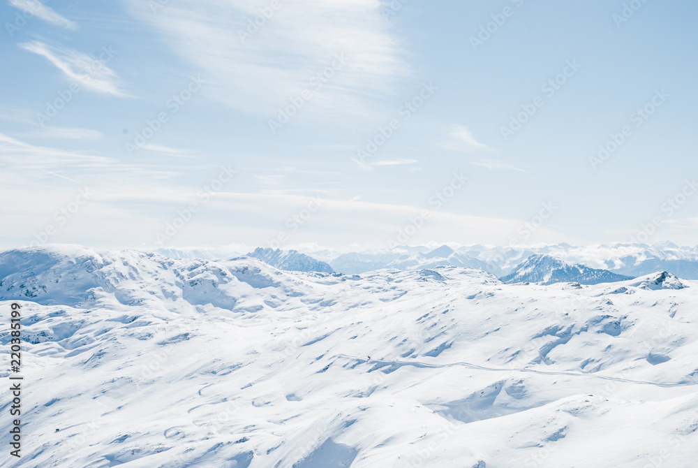 Snowy winter landscape in the Austrian Alps. Rocky plateau covered by sunlight. Bright white light reflected by snow