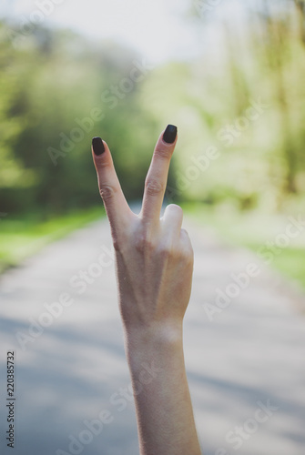 Girl demonstrating a number two (2) gesture against sunny green background. © Yurii Zymovin