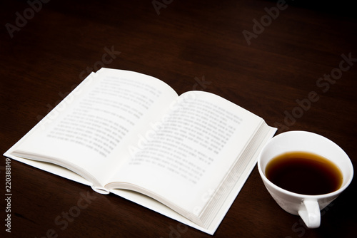 a book open on the desk with a cup of coffee.