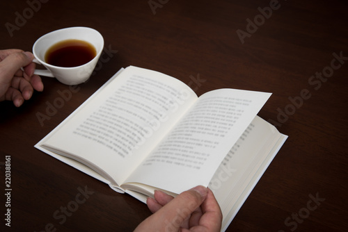 the man's hand reading with a cup of coffee in one hand.