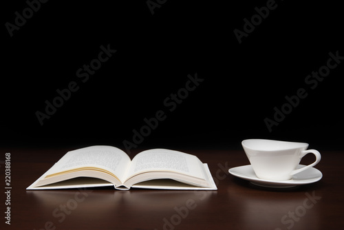 a book open on the desk with a cup of coffee.