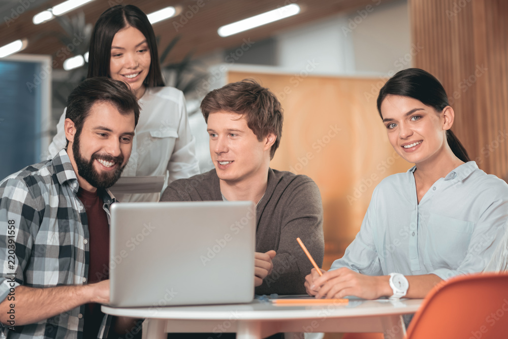 Pleasant collaboration. Joyful creative people sitting in front of the laptop while working together in team Pleasant collaboration. Joyful creative people sitting in front of the laptop while working together in team