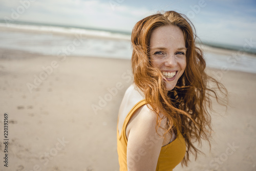Portrait of a redheaded woman, laughing happily on the beach photo