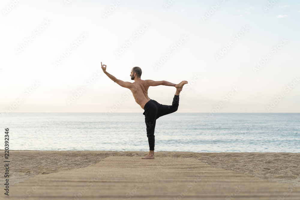 Spain. Man doing yoga on the beach in the evening, dancer position Spain. Man doing yoga on the beach in the evening, dancer position