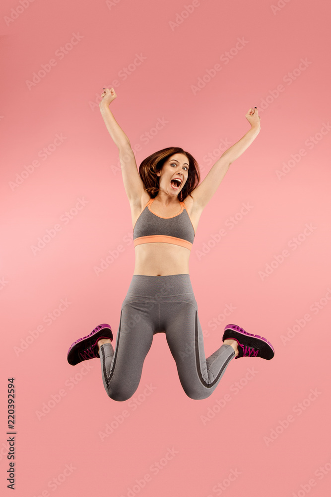 Freedom in moving. Mid-air shot of pretty happy young woman jumping and gesturing against orange studio background. Runnin girl in motion or movement. Human emotions and facial expressions concept