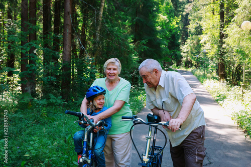 active senior couple with little granddaughter on bikes in nature