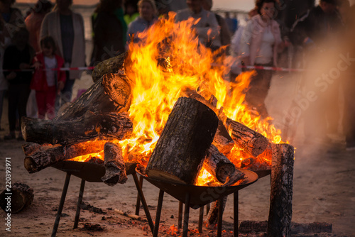 Large burning bonfire with soft glowing flame and sparkles flying all around. Romantic summer evening  people relaxing and enjoying calmness at the seaside during the Night of ancient lights