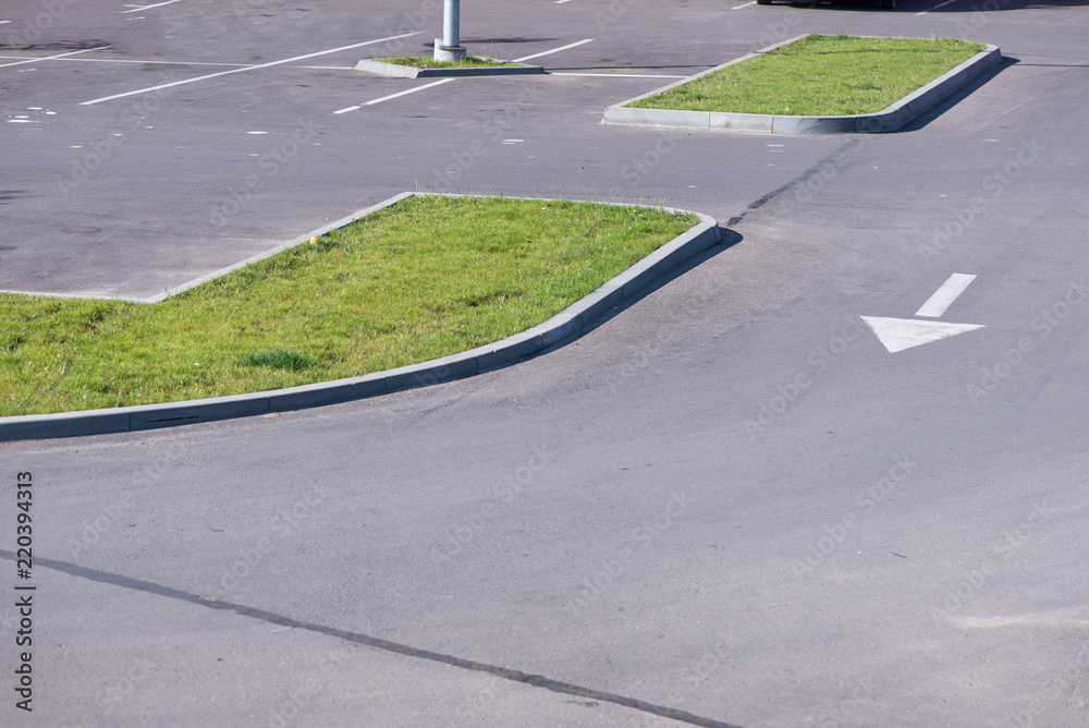 Obraz premium Newly made parking lot next to shopping mall in city centre with green areas. Arrows and signs on asphalt showing directions