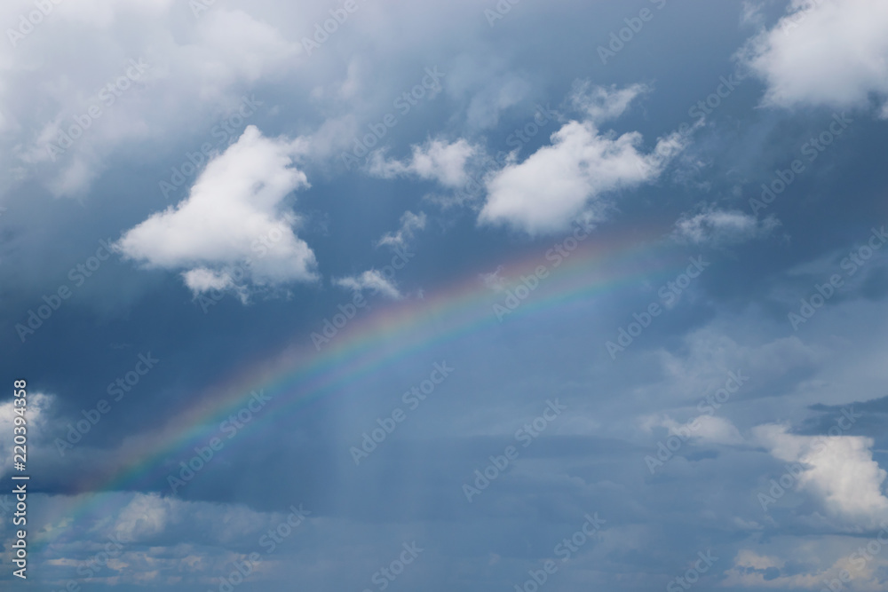 Colorful rainbow in the cloudy sky after rain.