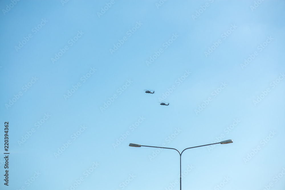 Military helicopters flying in the sky over a city and crowded event, taking photos, filming from above on clear blue sky background. An Isolated helicopter. Team of rescuers searching for lost people Military helicopters flying in the sky over a city and crowded event, taking photos, filming from above on clear blue sky background. An Isolated helicopter. Team of rescuers searching for lost people
