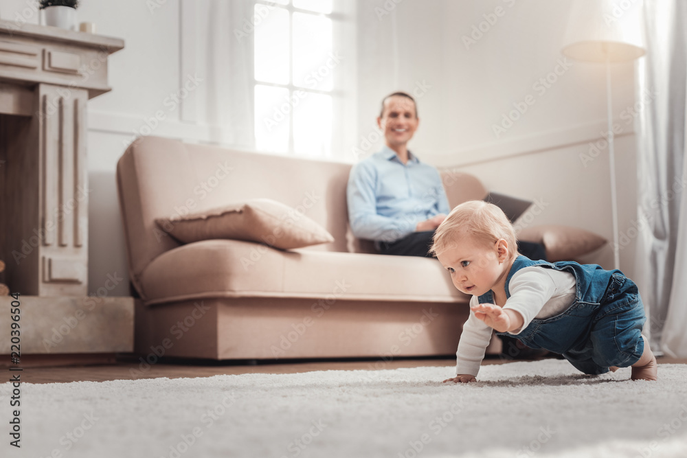 In the movement. Cute positive child crawling while exploring the room In the movement. Cute positive child crawling while exploring the room