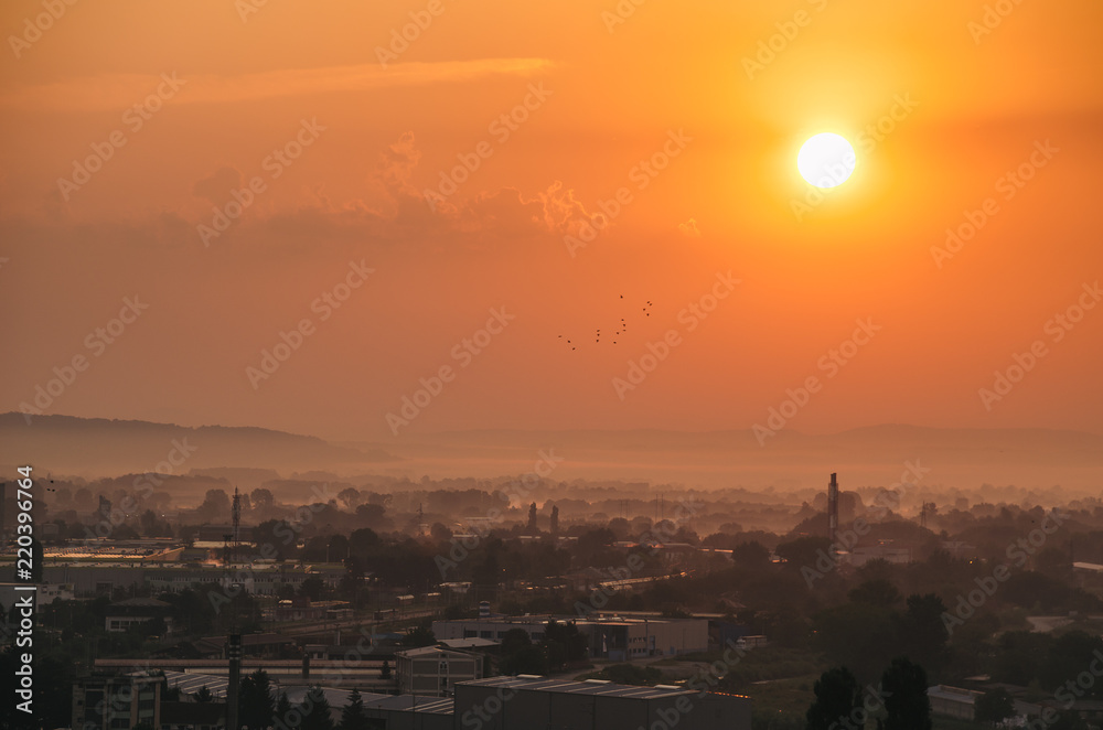 Golden sunrise above the city in the mist