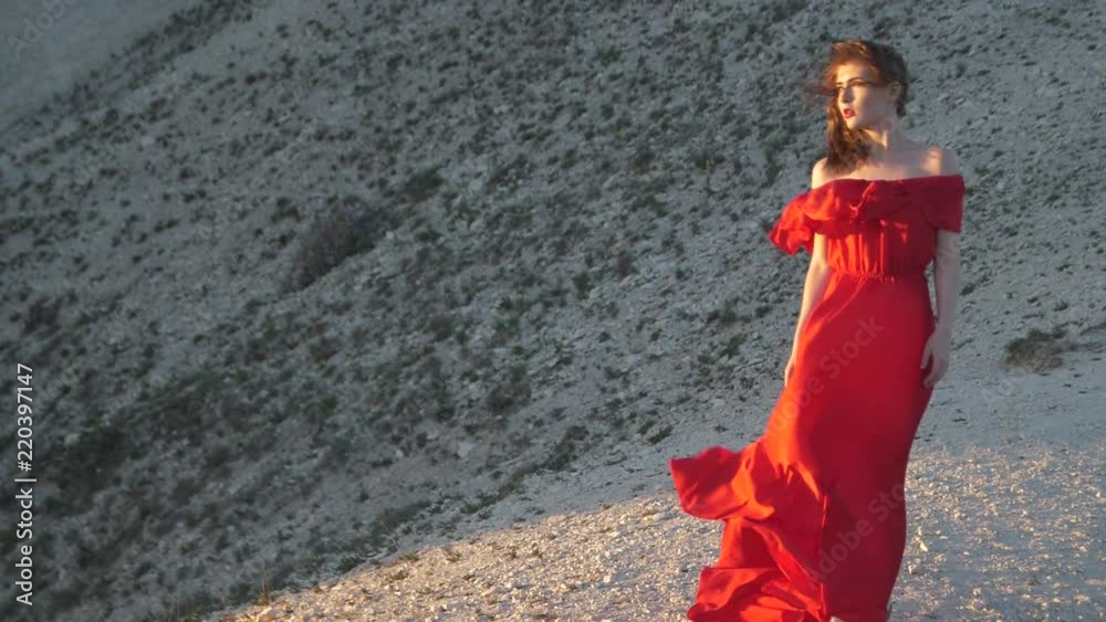 Young woman in red tunic looks at sun Blowing wind Young woman in red tunic looks at sun Blowing wind