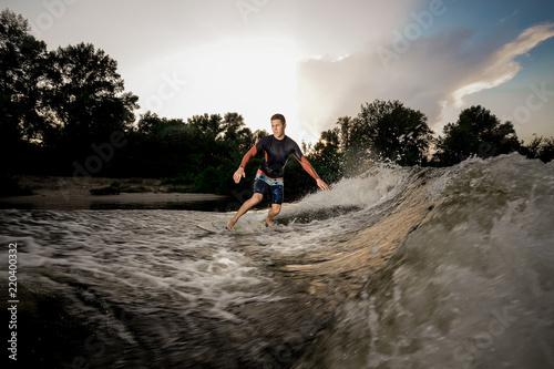 Fototapeta Naklejka Na Ścianę i Meble -  Young attractive active man riding on the wakeboard on the lake