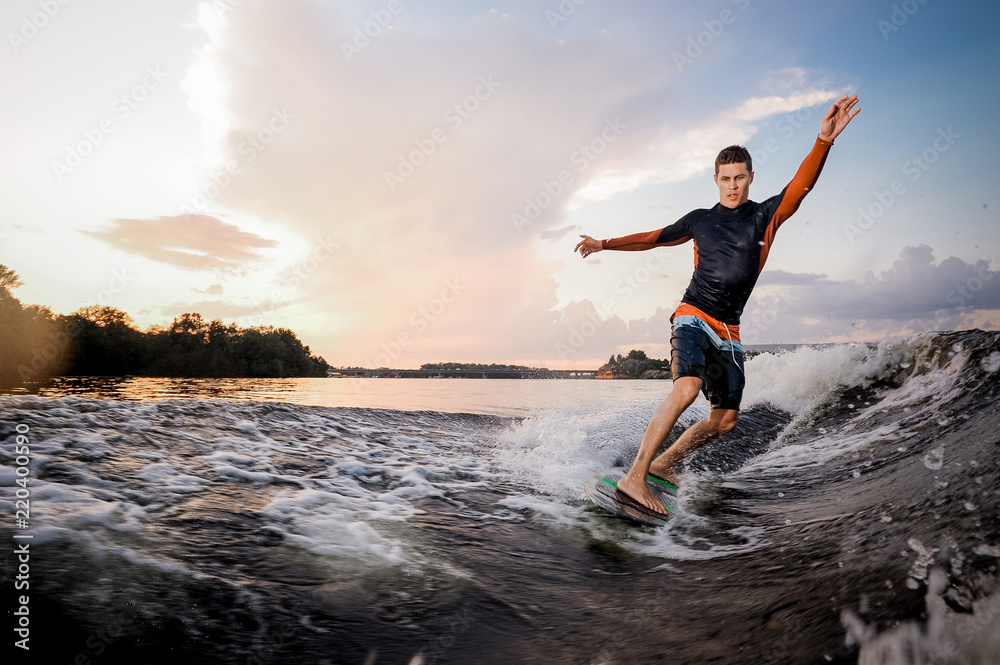 Young attractive man riding on the green wakeboard