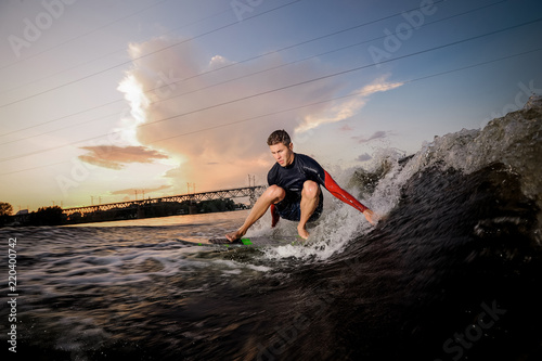 Active male wakeboarder riding on the bending knees on the board