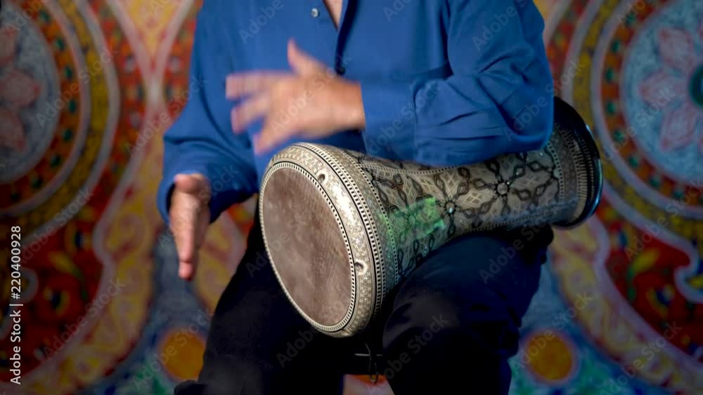 Wide shot of playing rhythms on doumbek drumming slow rhythm with arabic background.