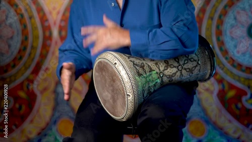 Wide shot of playing rhythms on doumbek drumming slow rhythm with arabic background. photo
