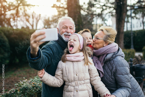 Grandparents taking selfie photo with their grandchildren in city park. photo