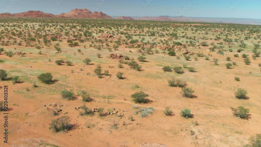 4K scenic backward flight, over green grassland savanna to ancient red rock formations 4K scenic backward flight, over green grassland savanna to ancient red rock formations