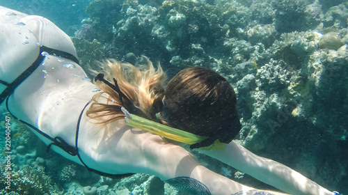 Girl swims near coral in red sea.