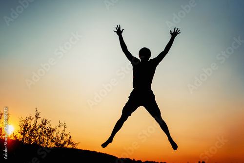 Happy man jumping for joy at sunset. Success and happiness concept