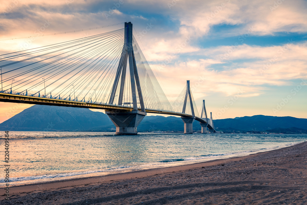 Obraz premium Dramatic evening scene with Rion-Antirion Bridge. Colorful spring scene of the Gulf of Corinth, Greece, Europe. Beauty of countryside concept background. Artistic style post processed photo.