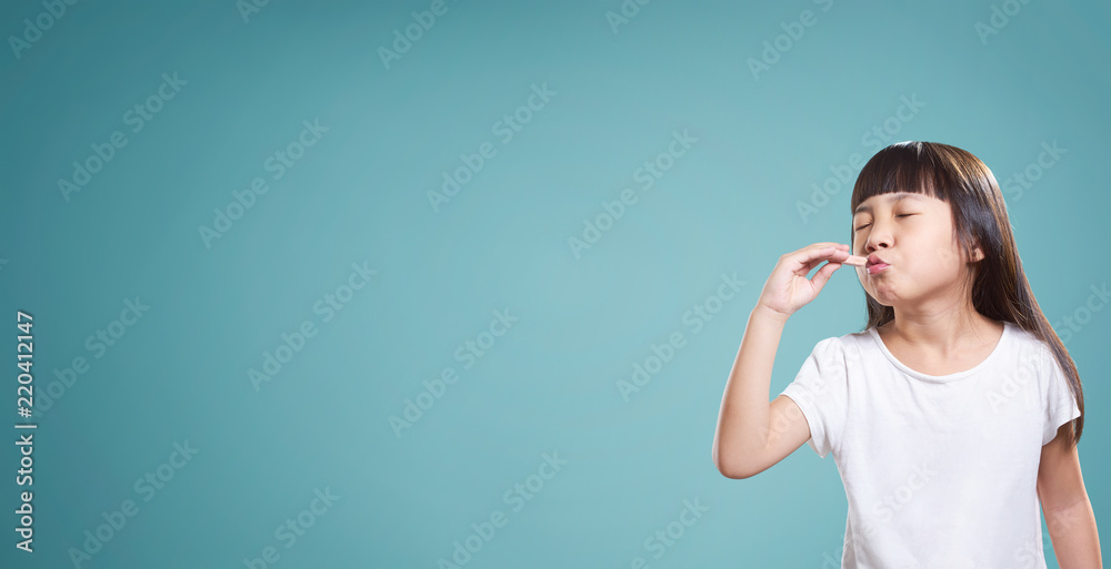 Panorama portrait of asian little happy girl with good taste chocolate . isolated on light blue background . Panorama portrait of asian little happy girl with good taste chocolate . isolated on light blue background .