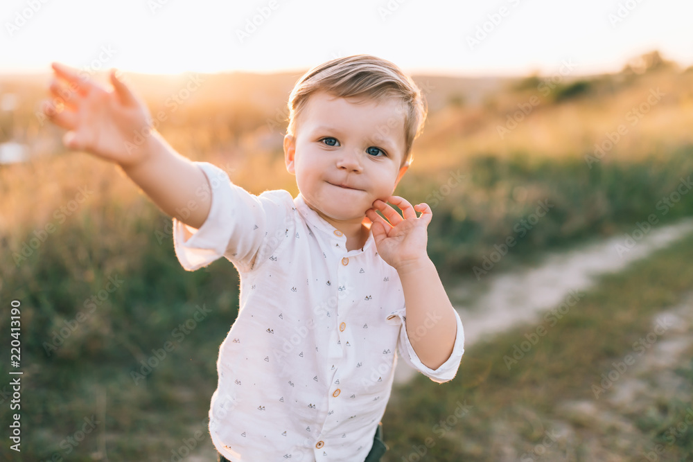 adorable little child smiling at camera while walking outdoors at sunset adorable little child smiling at camera while walking outdoors at sunset