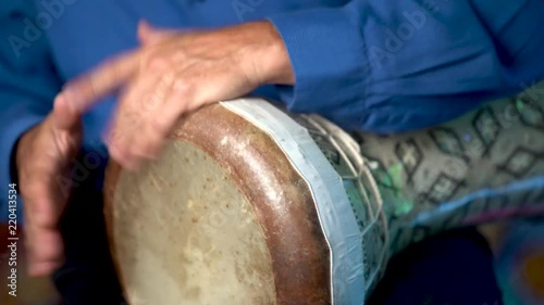 Closeup of hands playing fast rolling rhythm on clay doumbek with fish skin head. photo