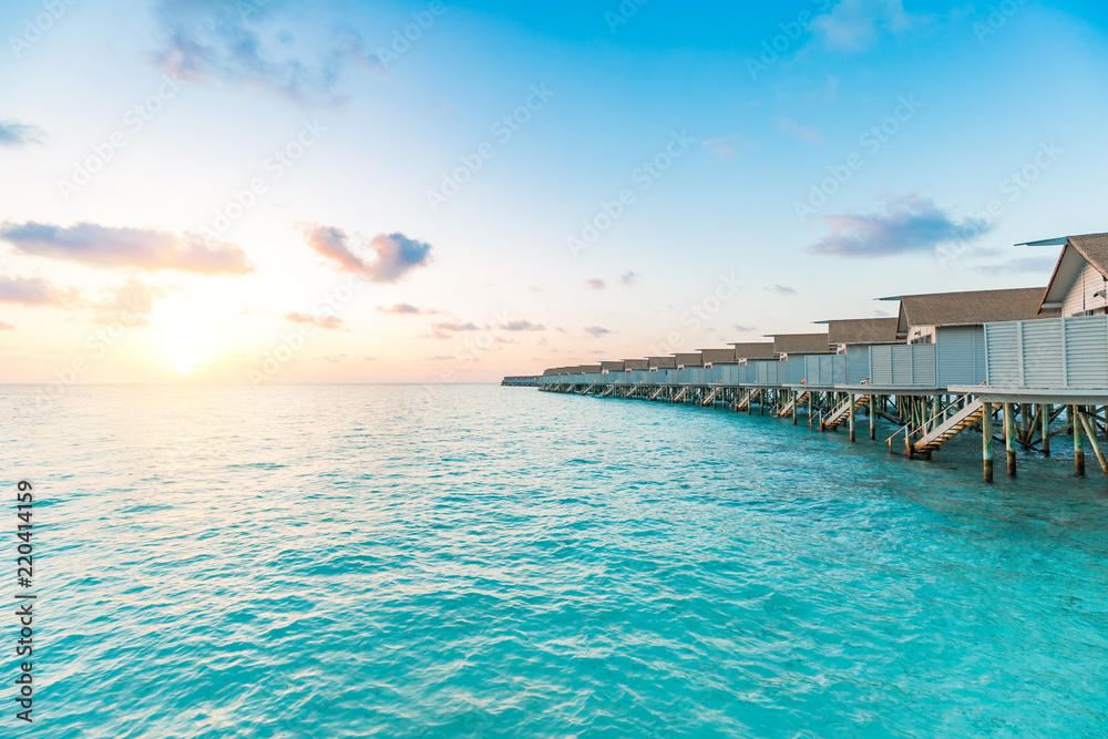 Obraz premium Beautiful villas over water on tropical island resort in Maldives with turquoise sea and sunset,Vacation in holiday relax with nature in summer