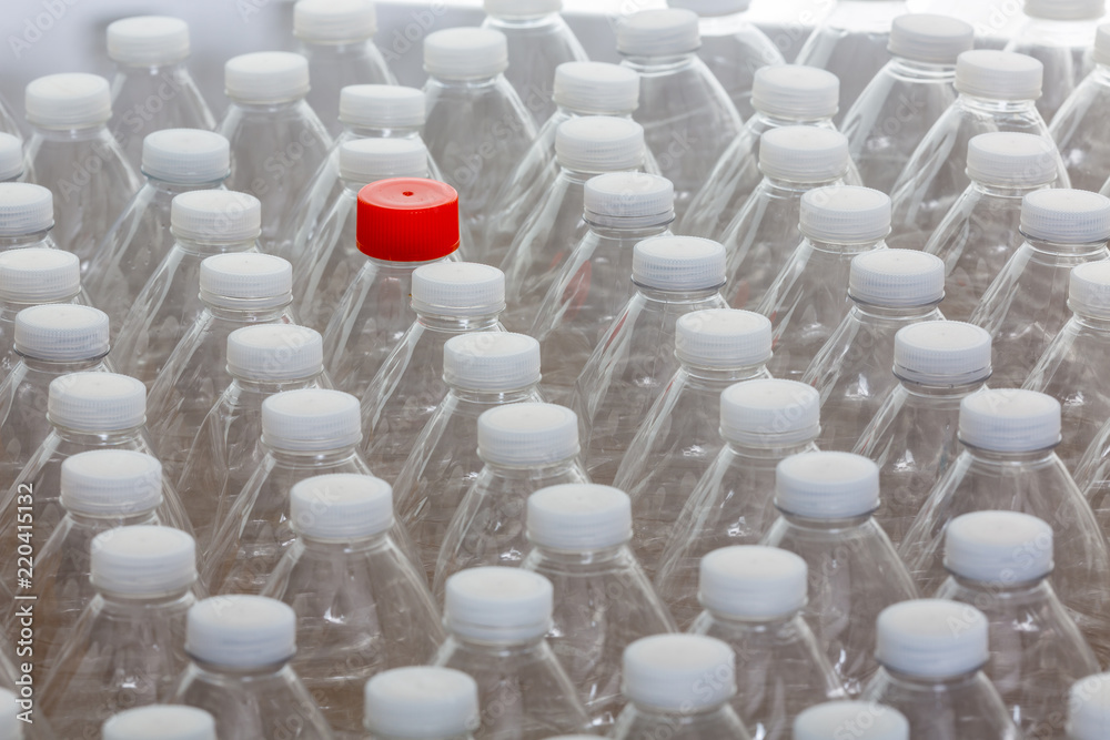 Fototapeta premium Multiple white capped plastic bottles with one red