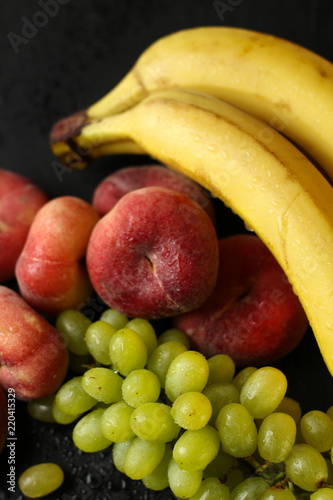 Fruit placement on a black background, grapes, grapes, bananas, peaches.