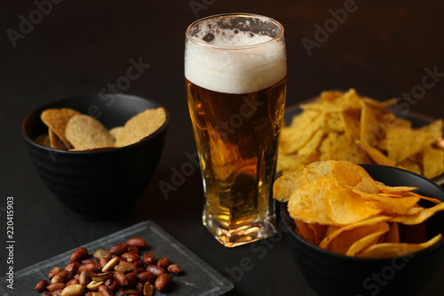 Light beer in a glass bowl on a black background.Beer in the bar and snacks  chips  nuts.