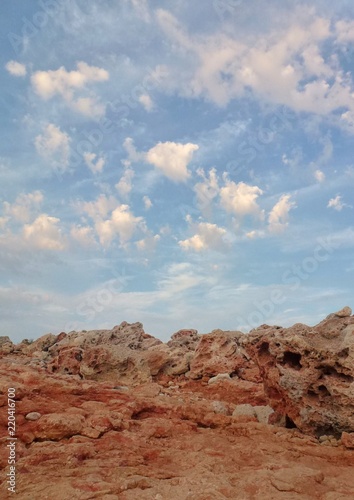 Red stones and a gentle blue sky with clouds