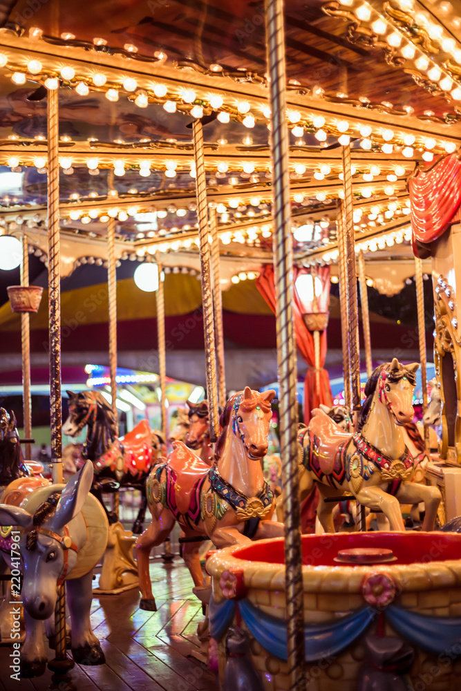 Front view of a stopped carousel at night. In this photo: Warm colors, horses toy, happiness, fun, childhood and night photography.