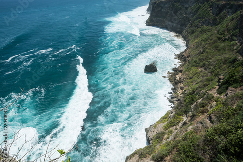 cliff steep with waves and surf in uluwatu temple blue water in bali indonesia photo